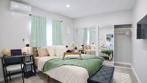 Een moderne slaapkamer met een bed, nachtkastje, lamp en een spiegel.