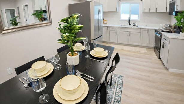Een moderne keuken met witte kasten, een groot eiland en een eethoek voor zes personen.