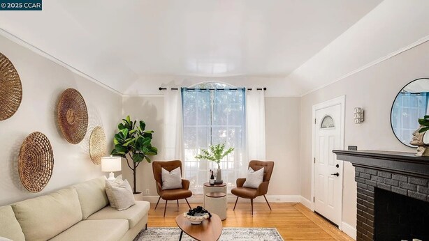 Una sala de estar con un sofá, dos sillones, una mesa de centro, chimenea y un ventanal con cortinas.