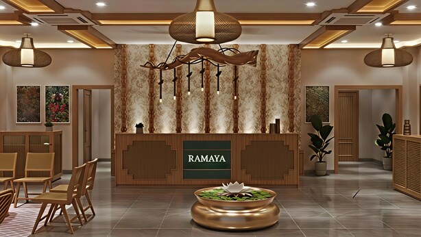Un comptoir d’accueil avec une enseigne portant l’inscription « RAMAYA », un lustre moderne et une composition florale décorative.