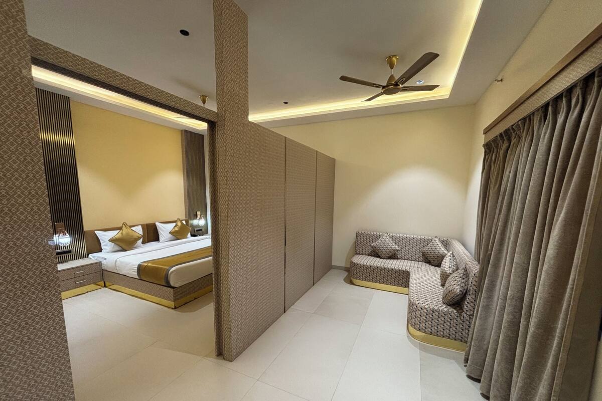 A modern hotel room with a bed, sofa, and a ceiling fan.