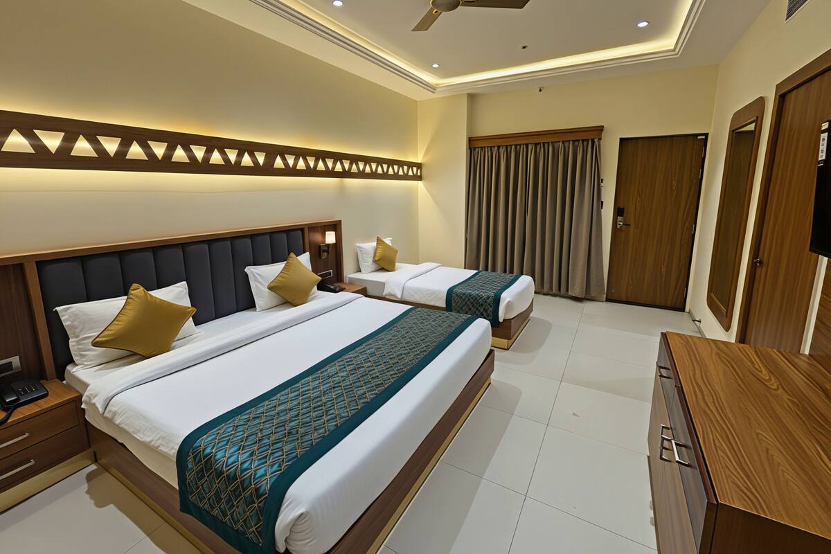 A hotel room with two beds, a ceiling fan, a TV, and a wooden cabinet.