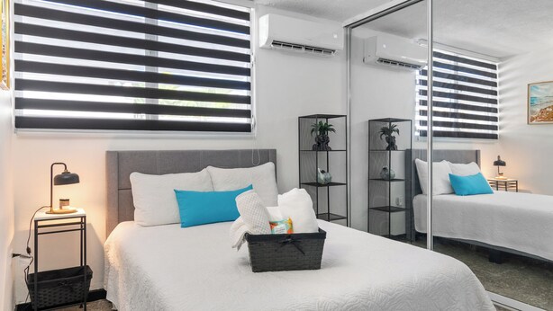 Una camera d'albergo con un letto, comodini, uno specchio e una finestra con tende.