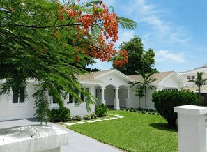 A white building with a covered patio and a well-maintained lawn.