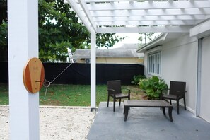 A covered patio with a swing set, two chairs, and a table. - Large tropical group retreat | Beach just steps away | Spacious modern home (Nassau)