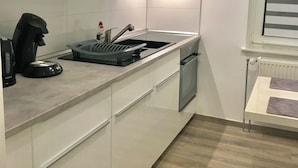 Eine moderne Küche mit weißen Schränken, einer Edelstahl-Spüle, einem Wasserkocher und einem Toaster.