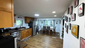 A kitchen with wooden cabinets, a stainless steel refrigerator, and a dining area with a table and chairs.