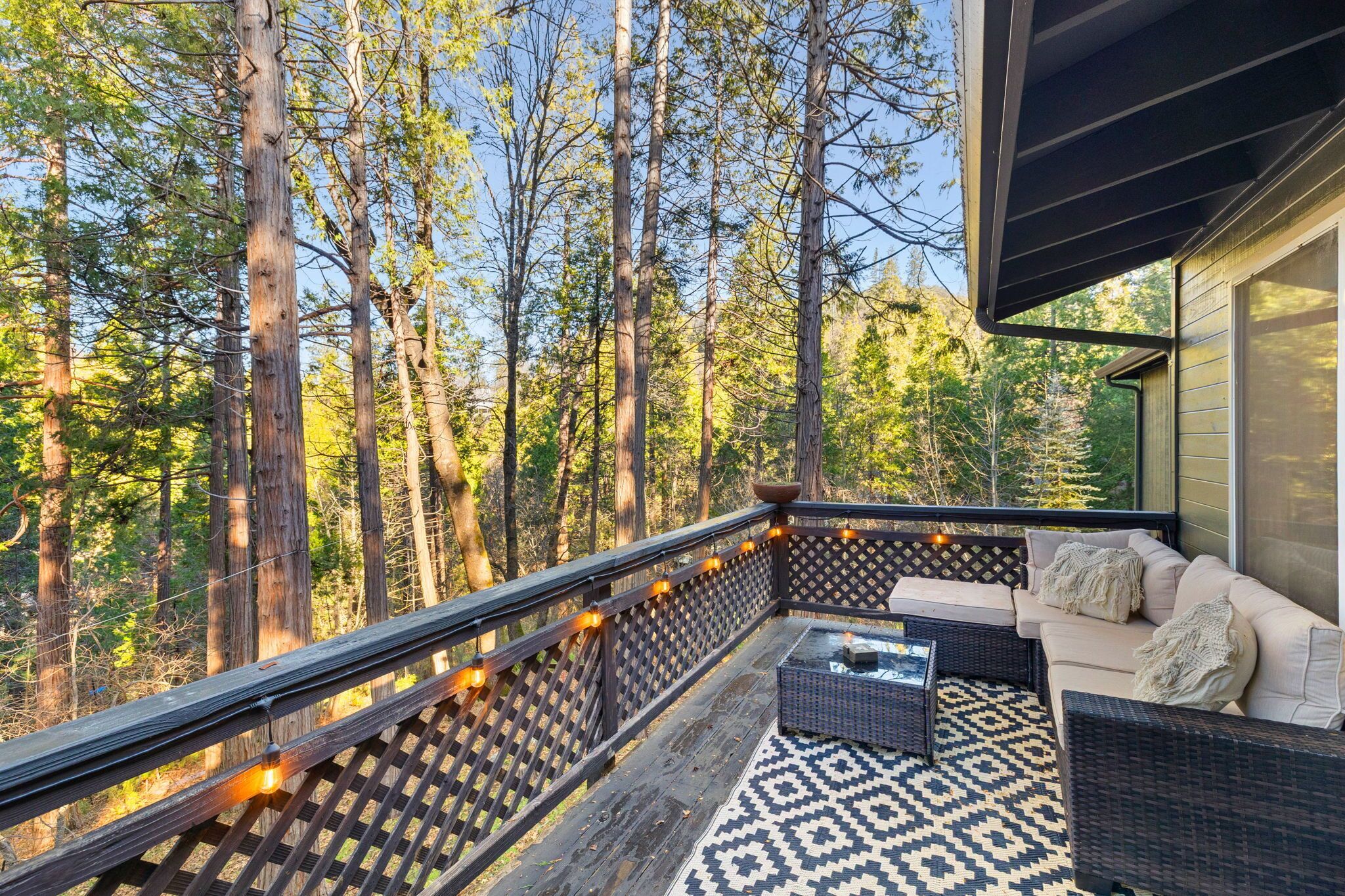 A balcony with a patterned floor, wicker furniture, and string lights.