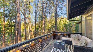A balcony with a patterned floor, wicker furniture, and string lights.