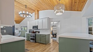 A spacious kitchen with wooden flooring, white cabinets, and a central island.