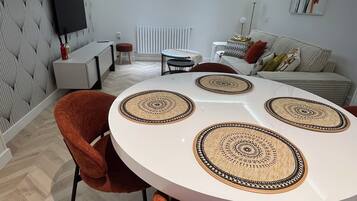 A modern dining area with a round table, orange chairs, and decorative mats.