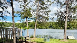 Ein Picknickplatz am Seeufer mit einer Holzterrasse, einem Picknicktisch und einer kleinen Holzhütte.