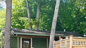 Eine Hütte mit Veranda, einem umzäunten Bereich und einem gepflasterten Weg.