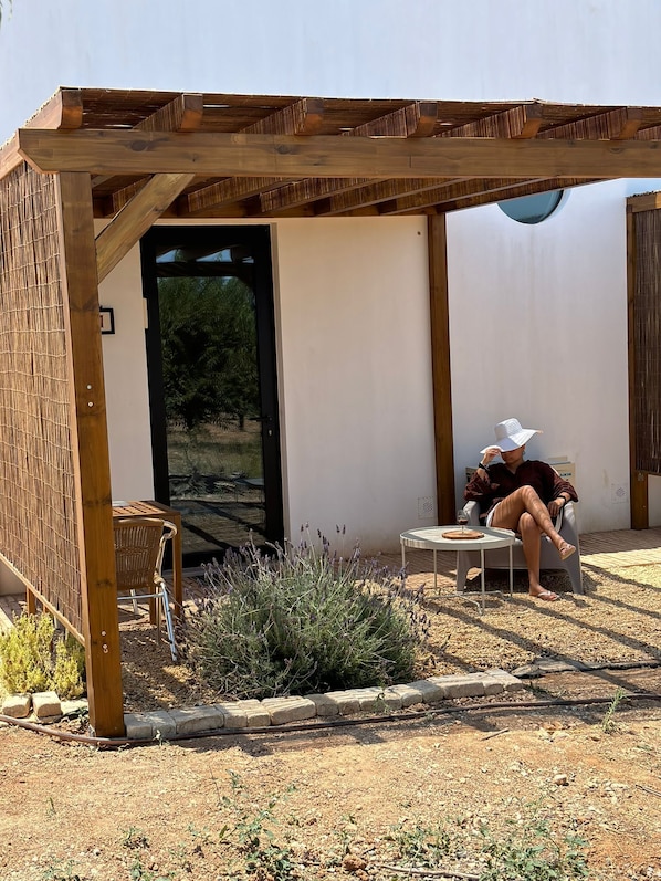Un espacio de estar al aire libre con techo, que incluye una mesa, sillas, una pérgola de madera y vistas del paisaje circundante.