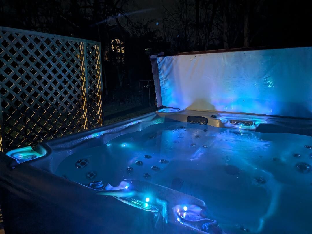 Ein Whirlpool mit integrierter Beleuchtung, umgeben von einem Gitterzaun.