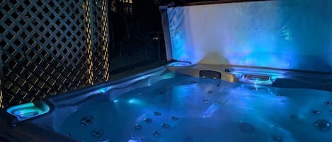 A hot tub with built-in lighting, surrounded by a lattice fence.