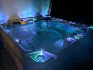 Een jacuzzi met ingebouwde verlichting en een houten bank.