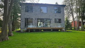 A modern two-story house with a stone facade, large windows, and a wooden deck.