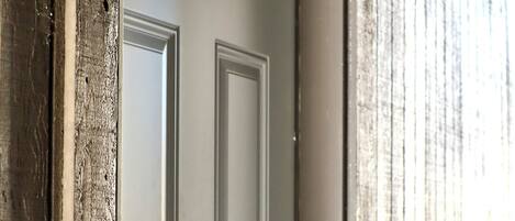 A white door with a letter "B" above it, set in a wooden exterior wall.