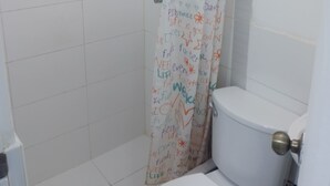 A bathroom with a white tiled floor, a white toilet, and a shower curtain with colorful text and drawings. - APARTMENT NEAR LOS INCAS GOLF COURSE AND THE U.S. EMBASSY LIMA - PERU (Lima)