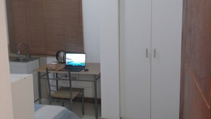 A bedroom with a bed, a desk with a laptop, a wardrobe, and a window with blinds. - APARTMENT NEAR LOS INCAS GOLF COURSE AND THE U.S. EMBASSY LIMA - PERU (Lima)