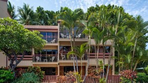 Un hotel de varios pisos con balcones, rodeado de vegetación tropical.