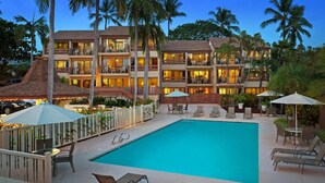 Un hotel con piscina, zona de estar al aire libre y varios balcones.