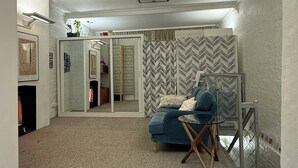 Una habitación amplia con alfombra estampada, un sofá azul y una pared con espejo.