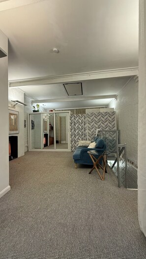 A spacious room with a patterned carpet, a blue sofa, and a mirrored wall. - Split-level Warehouse Conversion with gym equipment. Kings X Camden Regents Park (London)