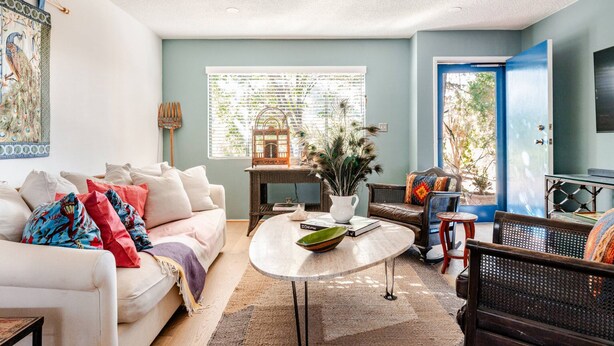 Ein Wohnzimmer mit einem weißen Sofa, einem Couchtisch und einer blauen Tür.