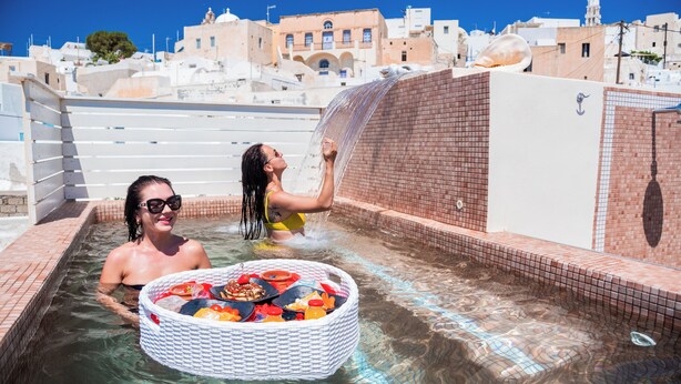 A swimming pool with a white tub filled with various items, surrounded by a tiled pool area. - Luxury Villas Hariton (Santorini)