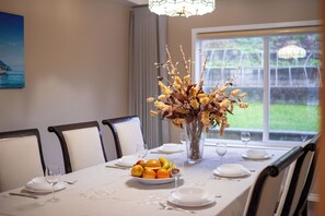 A dining table set with plates, glasses, and a fruit bowl.