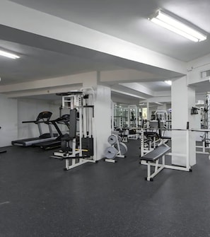 Un gimnasio con cintas de correr, máquinas de pesas y bancos.