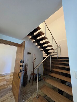 Una escalera moderna con escalones de madera y barandales de metal que conduce a un piso superior.