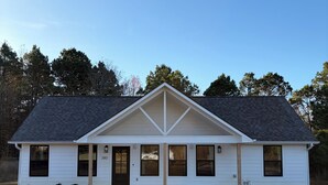A single-story house with a gabled roof, white siding, and a front porch with four windows. - Cimarron House in Holly Lake Ranch (Holly Lake Ranch)