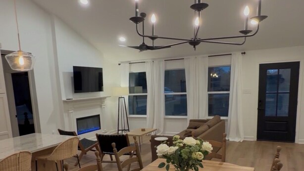 A dining area with a wooden table and chairs, a chandelier, and a fireplace. - Cimarron House in Holly Lake Ranch (Holly Lake Ranch)