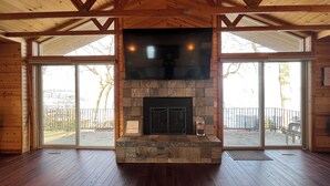Una habitación amplia con chimenea de piedra, ventanas grandes y vigas de madera.