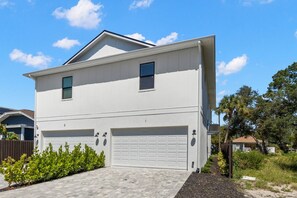 A two-story residential building with a garage, a driveway, and a well-maintained lawn. - Cherry St Chateau | Immaculate Home In Old West Tampa, 5 Min to Ray J (Tampa)