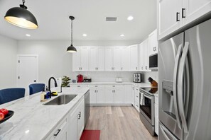 Una cocina moderna con armarios blancos, electrodomésticos de acero inoxidable y encimera de mármol.