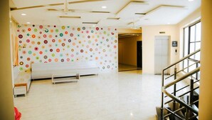 Un hall d’entrée spacieux, avec un mur orné de motifs, un banc et un escalier.