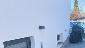 A modern building with a glass door, a set of concrete steps, and a small outdoor area with a covered table. - Guesthouse Wain- quiet, comfort, newly renovated.  Pet friendly! (Wain)