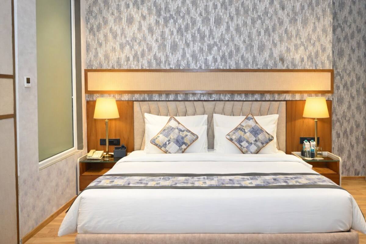 Una habitación de hotel con una cama grande, dos mesitas de noche y un cabecero.
