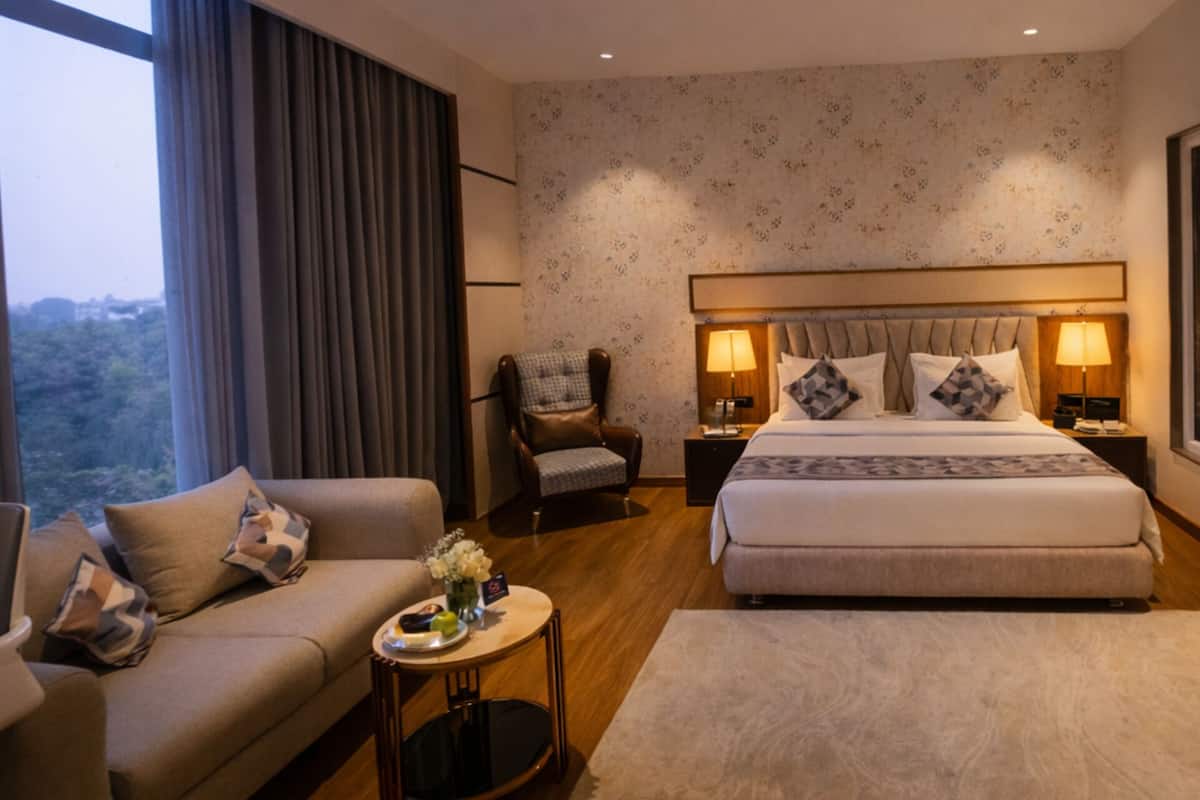 Una habitación de hotel moderna con una cama grande, un sofá, una silla y una mesita.