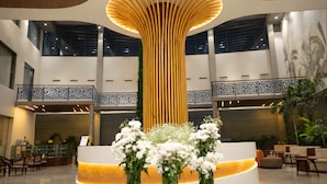 A modern lobby with a central reception desk, a high ceiling, and a decorative wooden structure. - The Aviyaan (Lucknow)