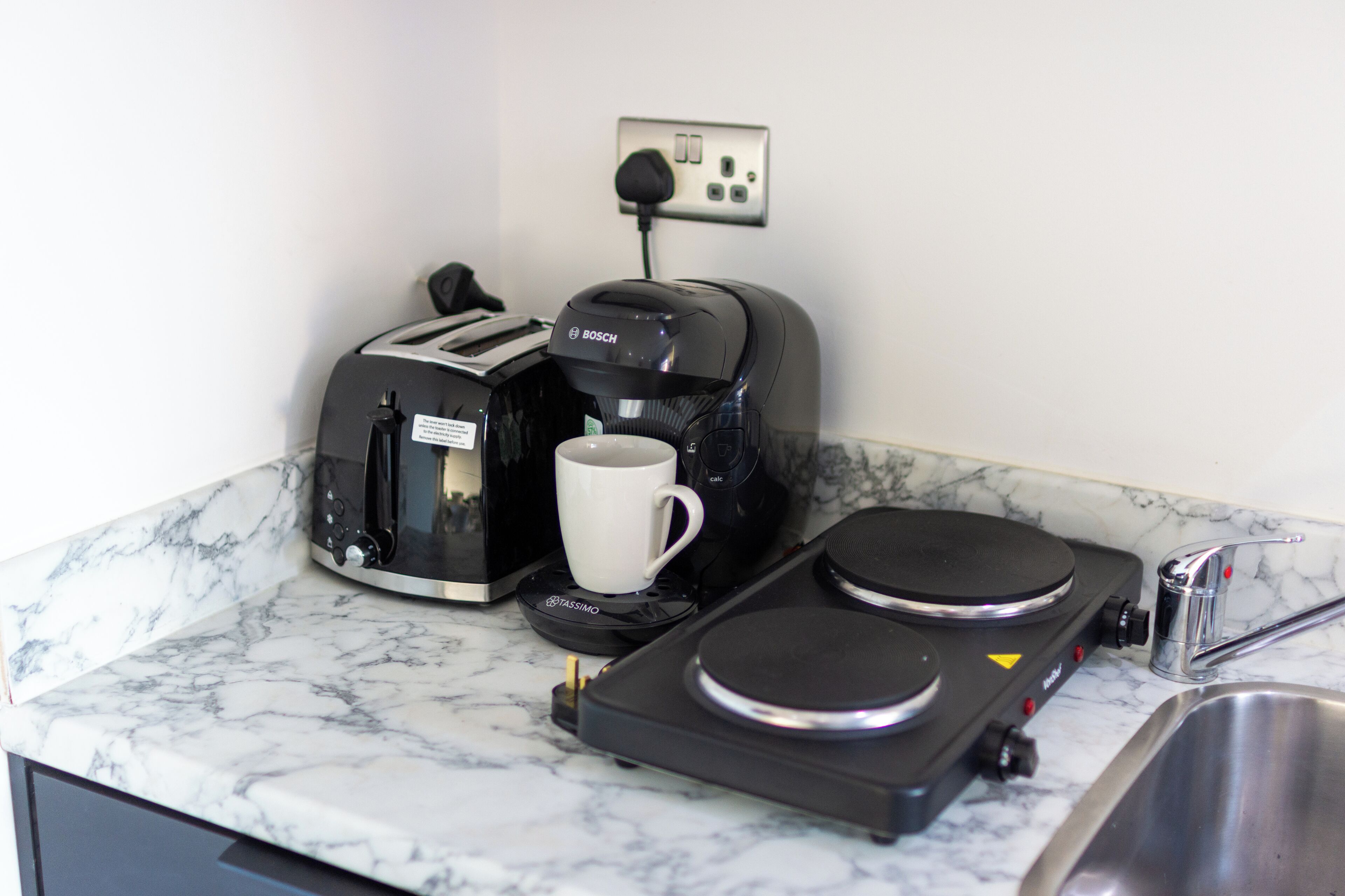 A kitchen with a coffee maker, toaster, and a sink.