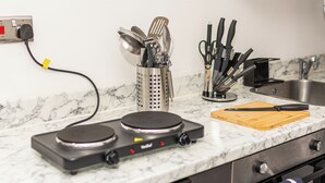 A kitchen with a stove, utensils, and a cutting board on a marble countertop. - Tooting Elite Studios, 5 Mints from Station (London)