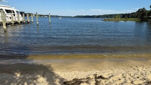 Ein Anwesen am Wasser mit einer Anlegestelle, Sandstrand und einem Boot.