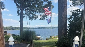 Ein Weg führt zu einem Gewässer, mit einer amerikanischen Flagge, einem Schild mit der Aufschrift 'HERALD HARBOR' und einem Schild mit dem Text 'AUF EIGENE GEFAHR'.