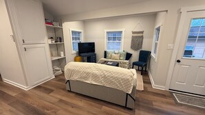 Ein kleines Schlafzimmer mit Bett, Schreibtisch, Stuhl und Fernseher.