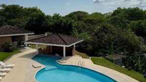 Una piscina con diseño curvo, rodeada por una terraza de concreto con sillas de descanso.